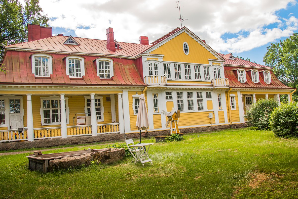 Myllylän kartanon keltainen päärakennus ja vehreä piha.